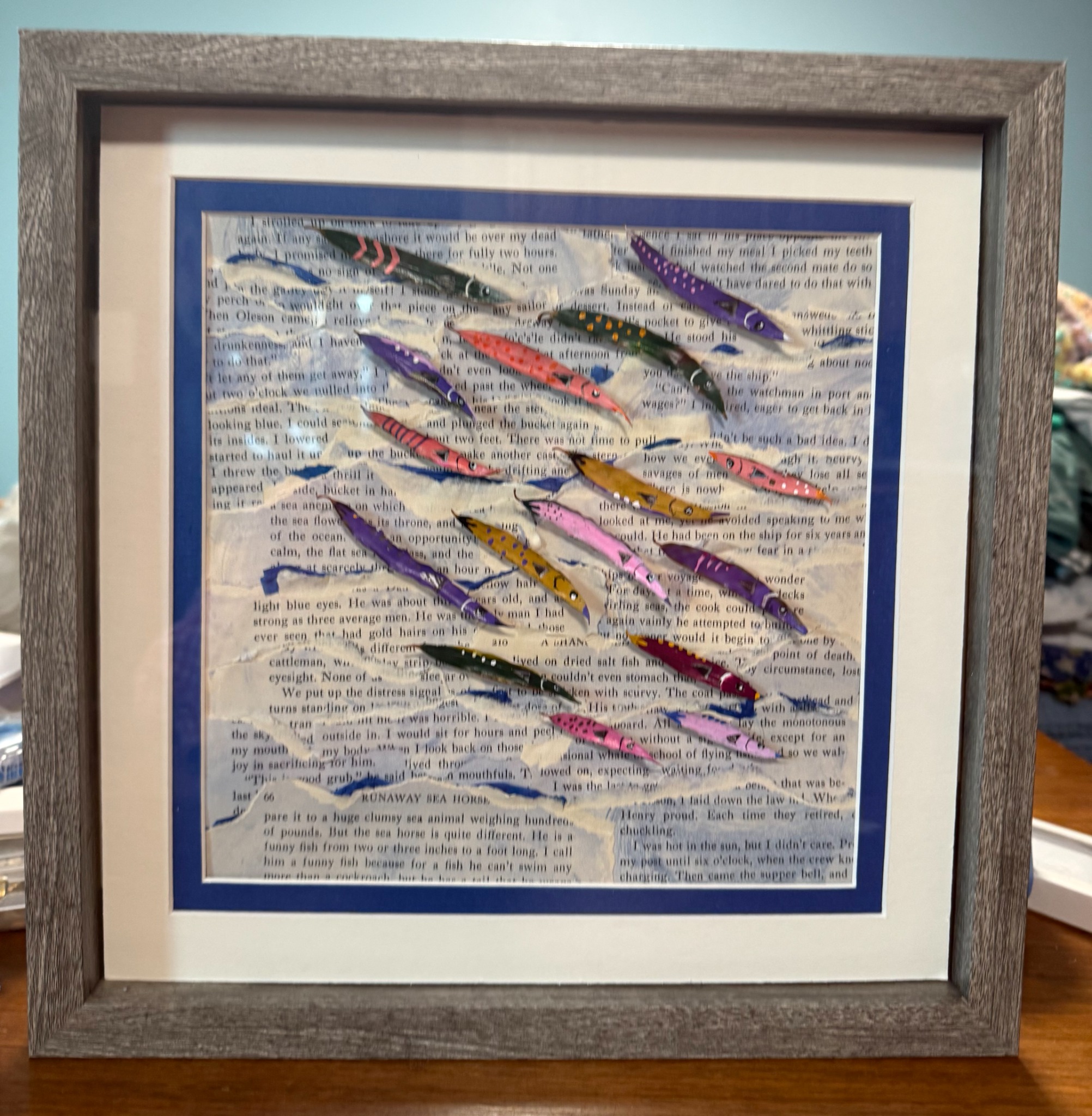 Errantes, a school of colorful fish made from painted leaves over old book pages